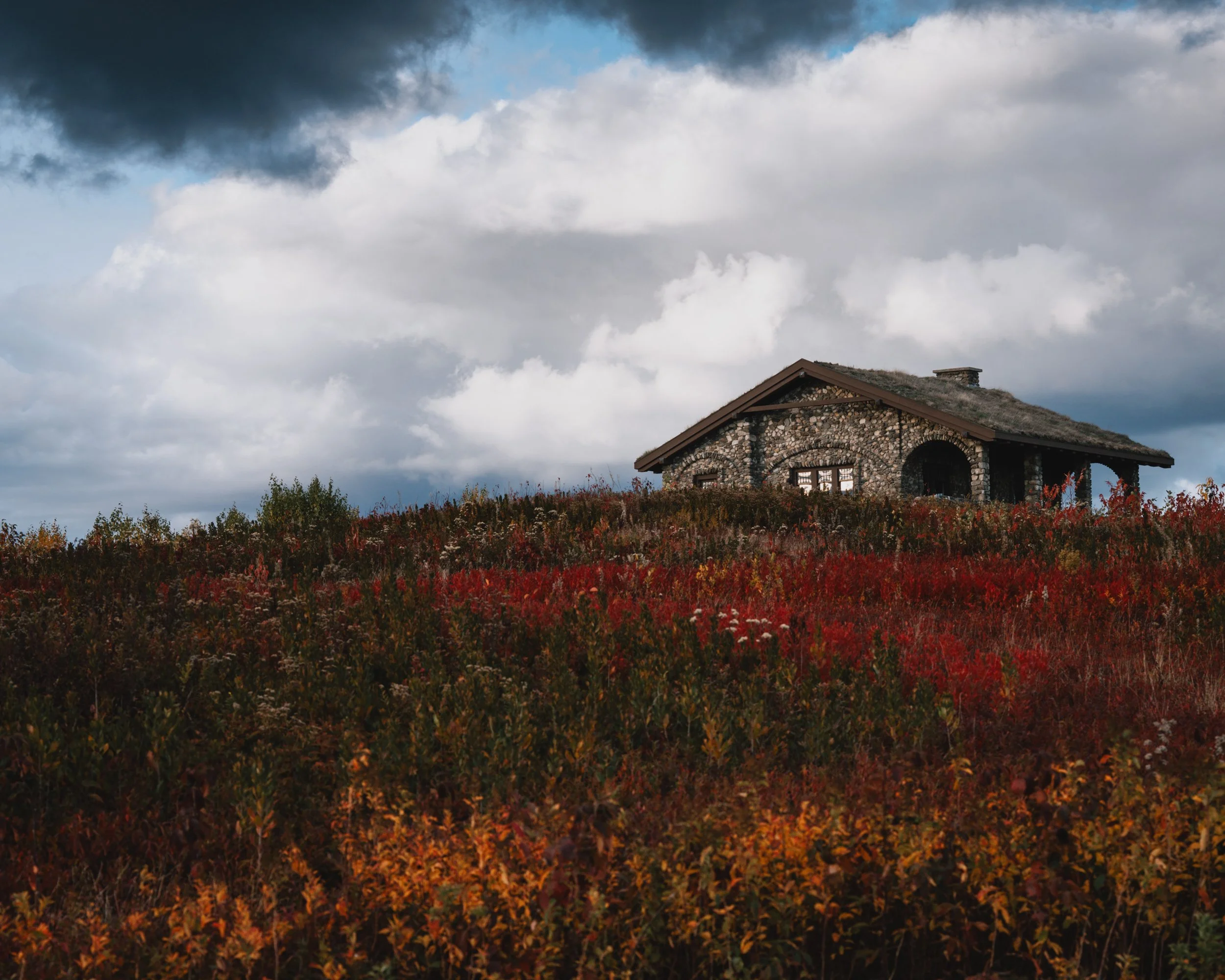 Beech Nut stone hut surrounded by red and orange fall foliage at Beech Hill Preserve in Rockport, Maine.