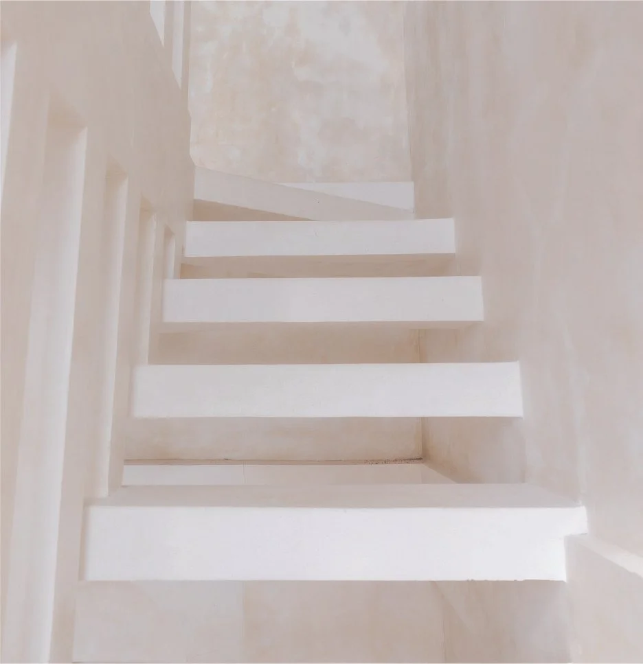 A staircase with white steps and a beige wall on the right side.