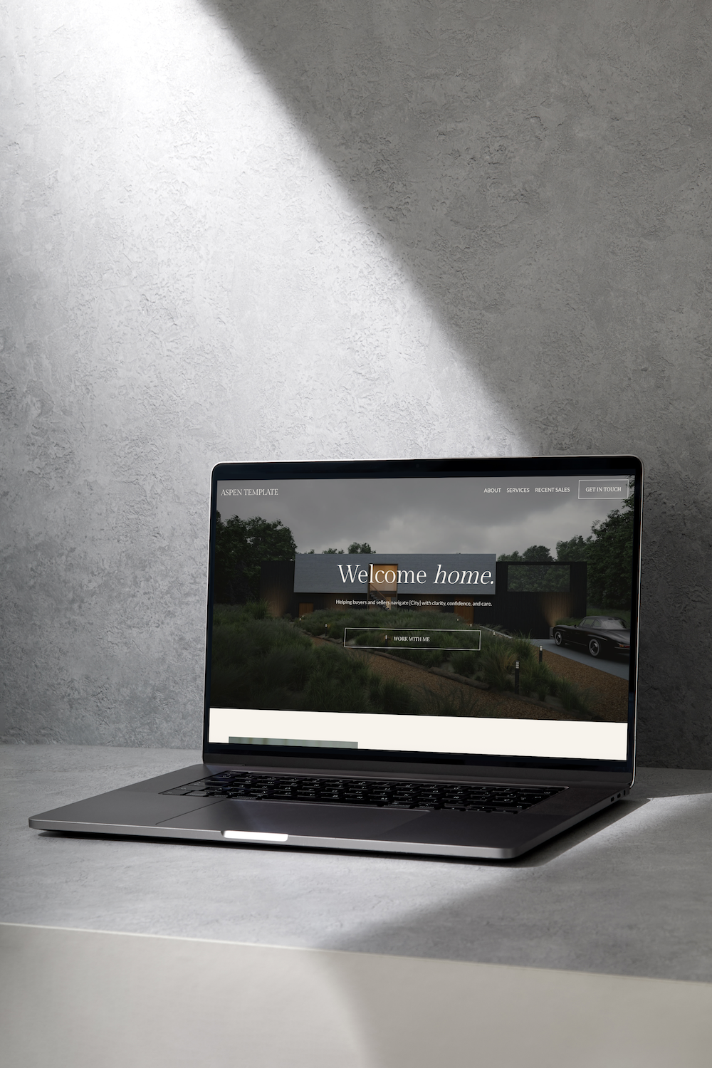 Laptop on a gray surface showing a real estate website with a house and car in the background.