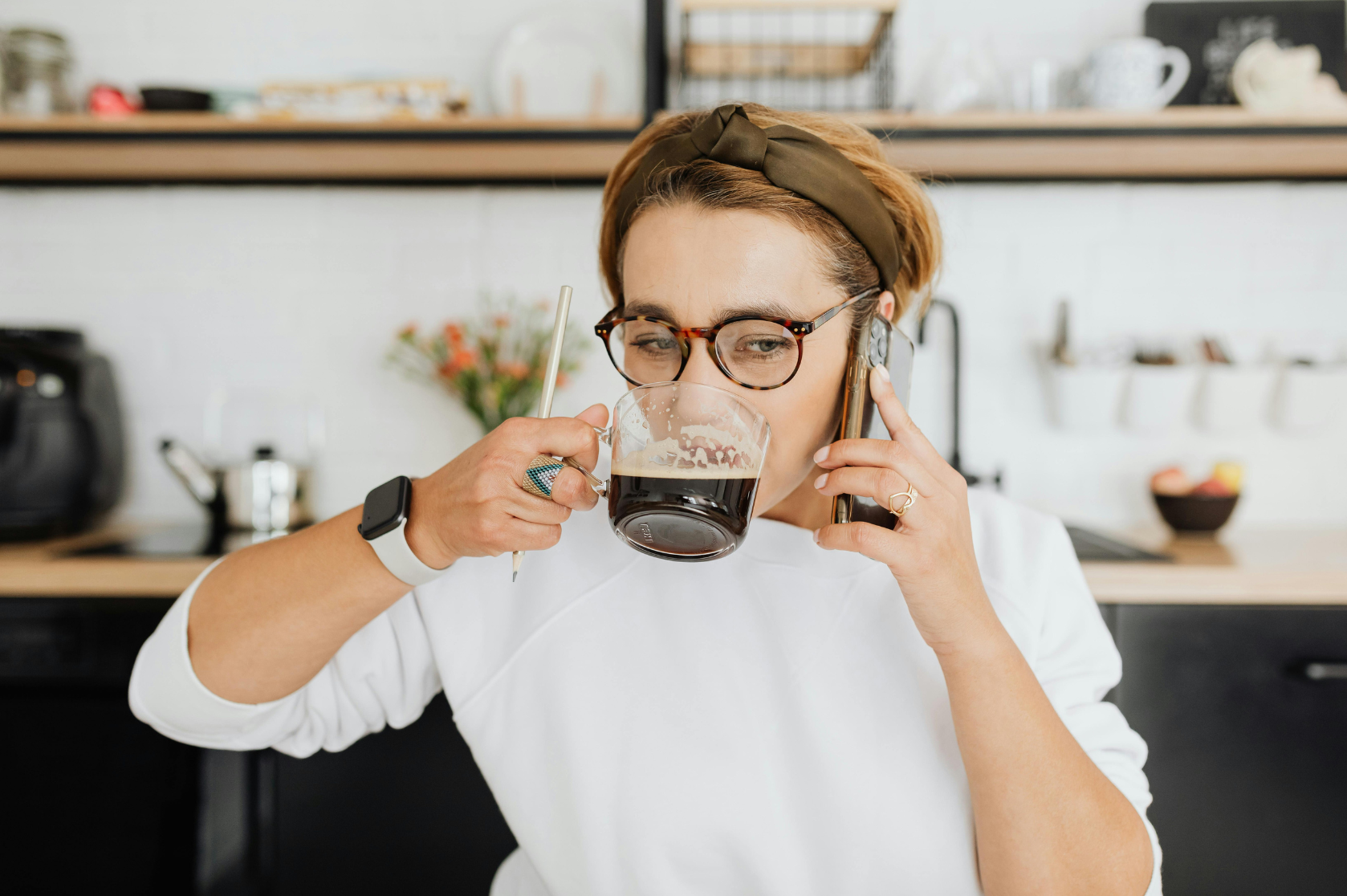 Woman multitasking, drinking coffee, holding pencil, talking on phone