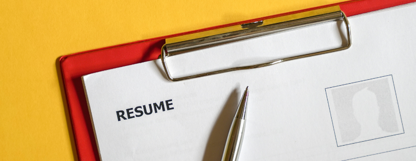 Resume on red clipboard with pen on yellow background