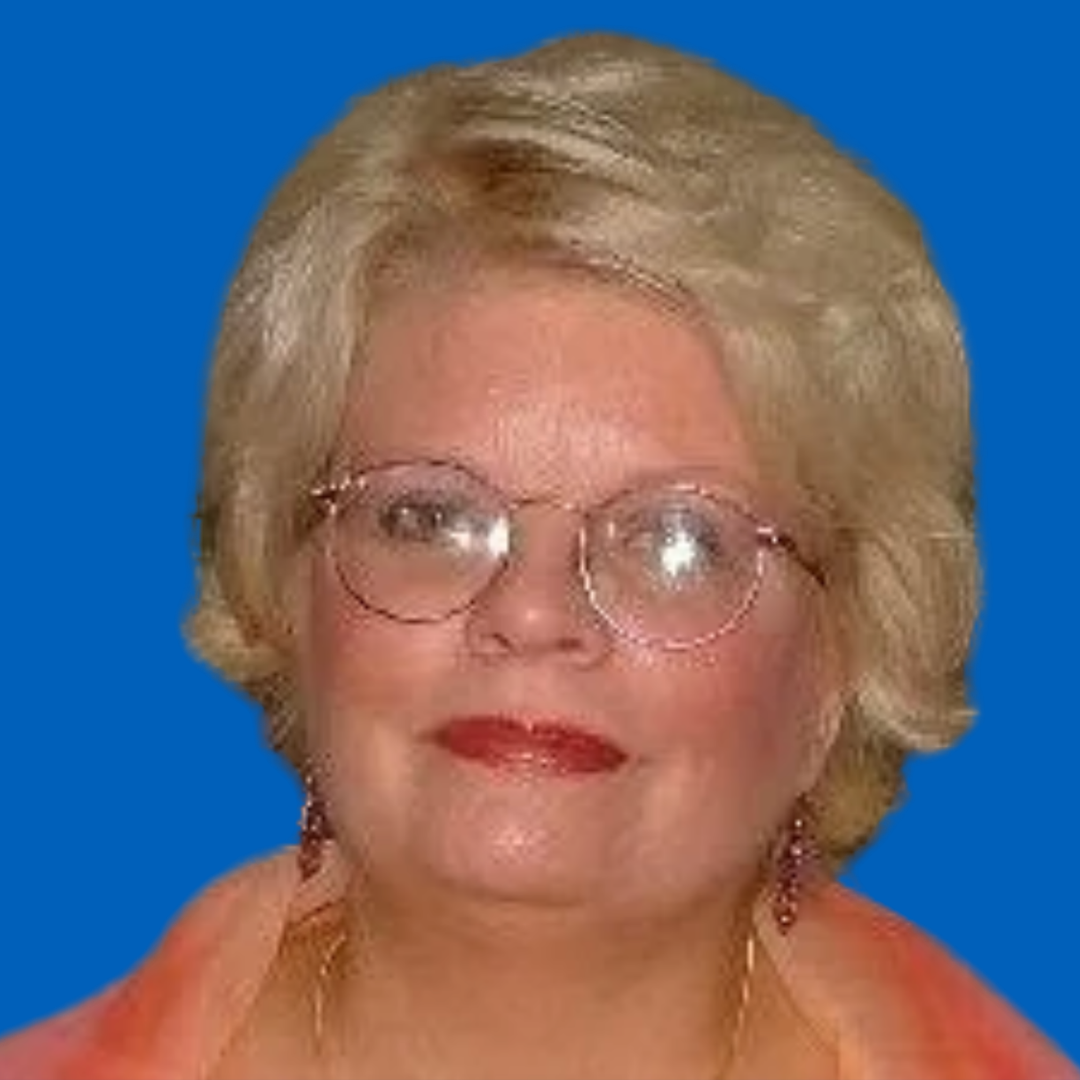 A portrait of an elderly woman with blonde hair, glasses, and red lipstick, smiling at the camera.