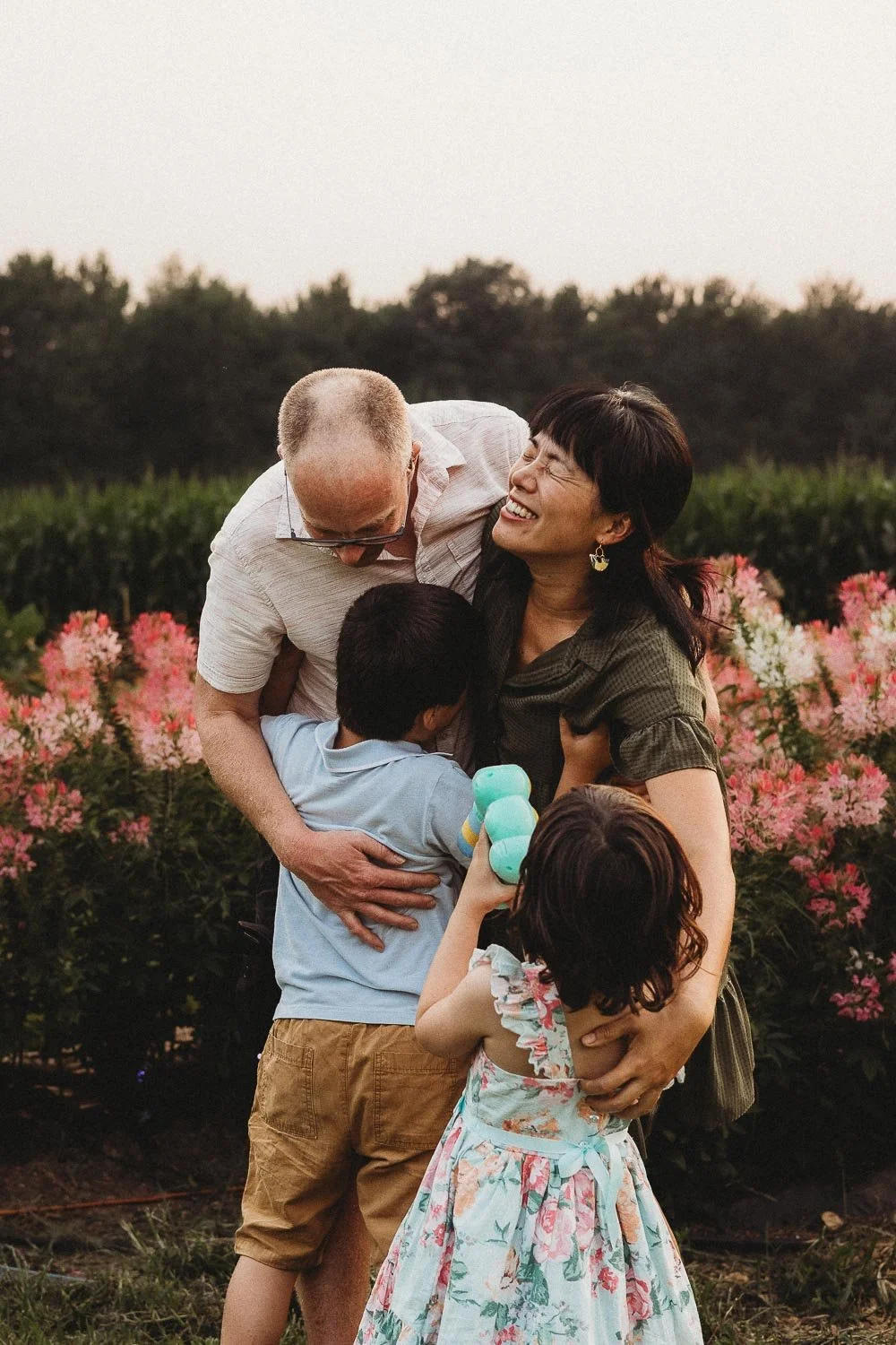 Family laughing while kids tickle parents during an outdoor family photoshoot at the Festifleur Montreal