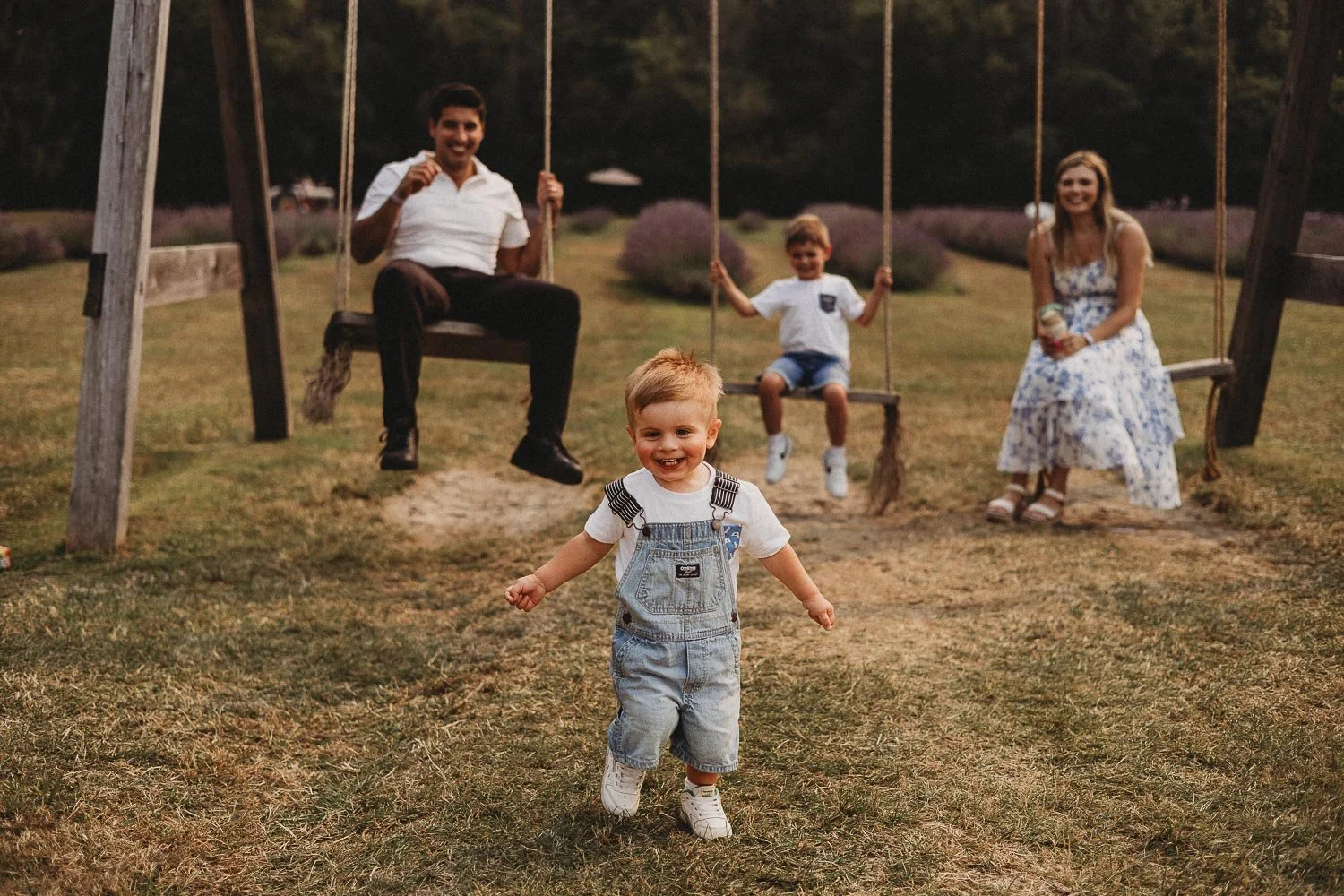 family smiling while boy runs towards the camera at an outdoor fmaily photoshoot in La Maison Lavande, St-Eustache