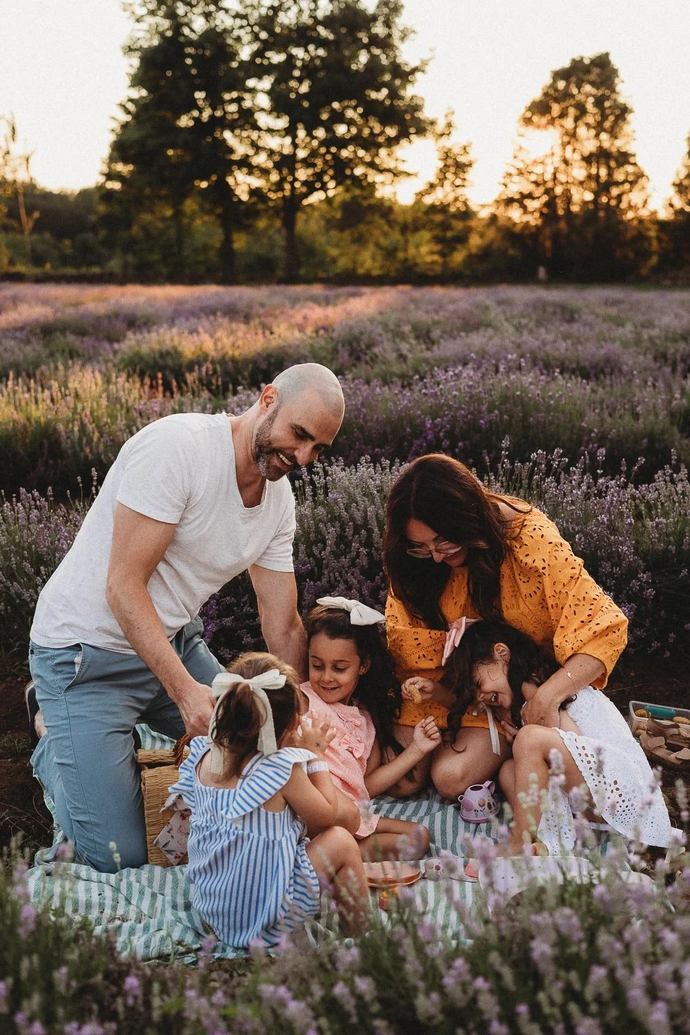Family of five tickling each other and laughing, captured during an outdoor family photoshoot at La Maison Lavande, St-Eustache