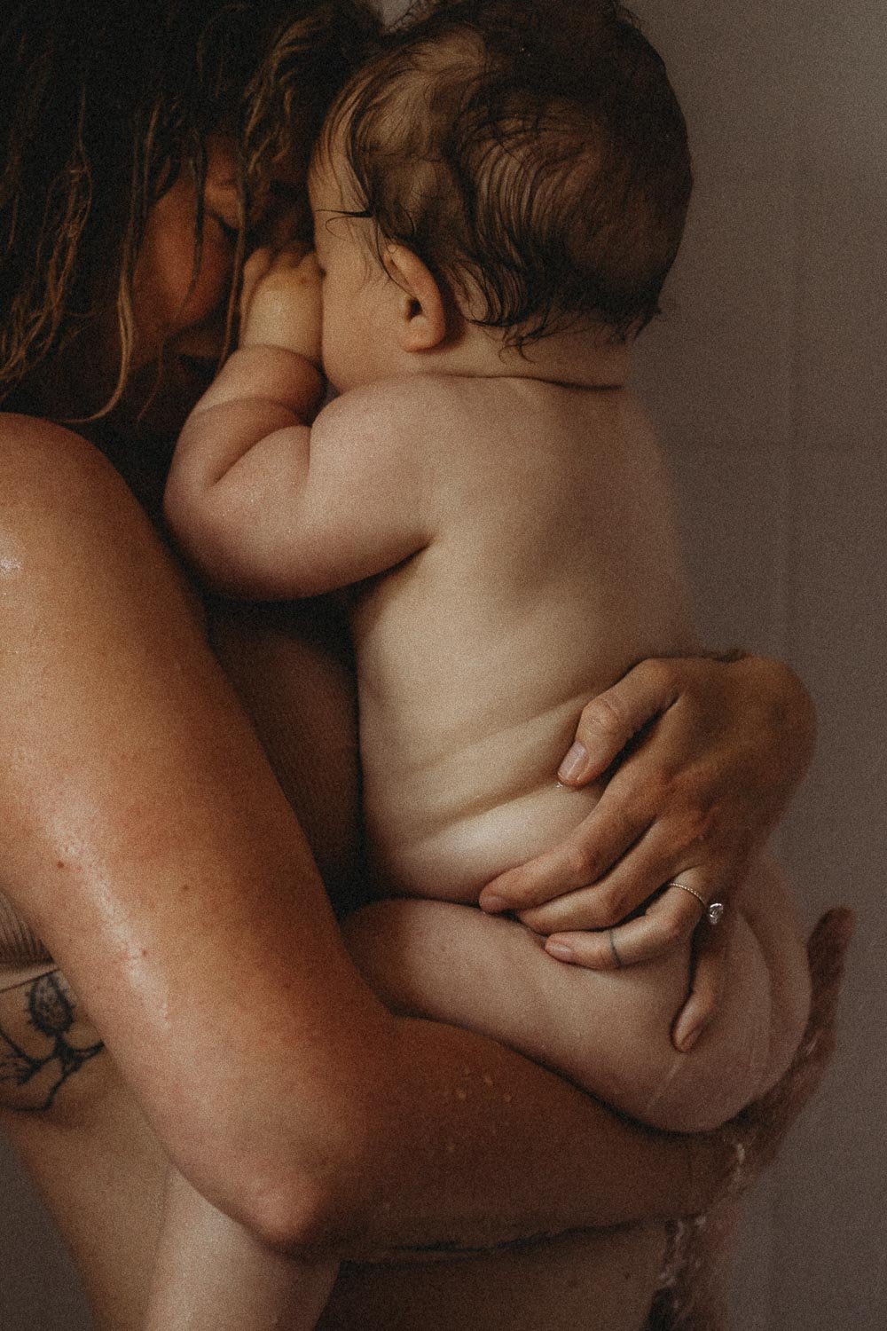 Mom and baby cuddling and touching faces while taking a shower in an intimate motherhood photoshoot in La Salle, Montreal
