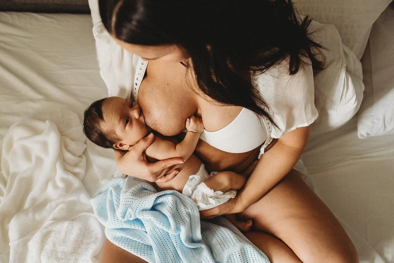 Mother breastfeeding at an in-home newborn photo session in Montreal