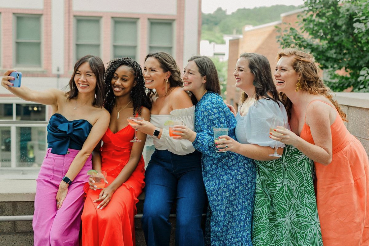 Women smiling and taking a selfie dressed in bright colour