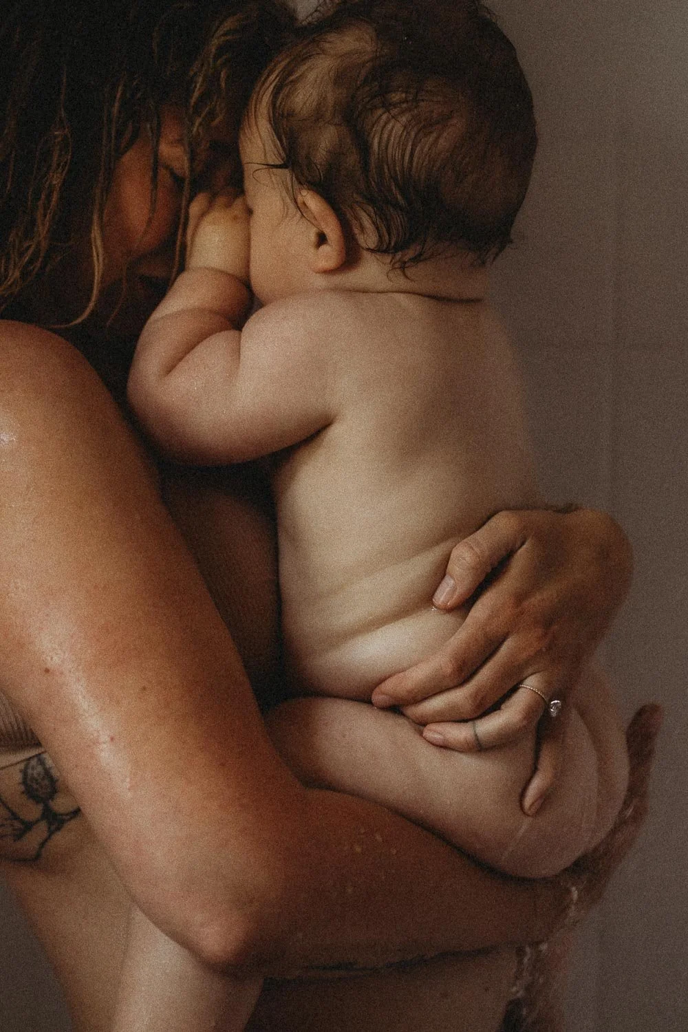 Mom and baby closely hugging in the shower, while baby is touching his mom's face, captured during an in-home motherhood photoshoot in La Salle, Montreal