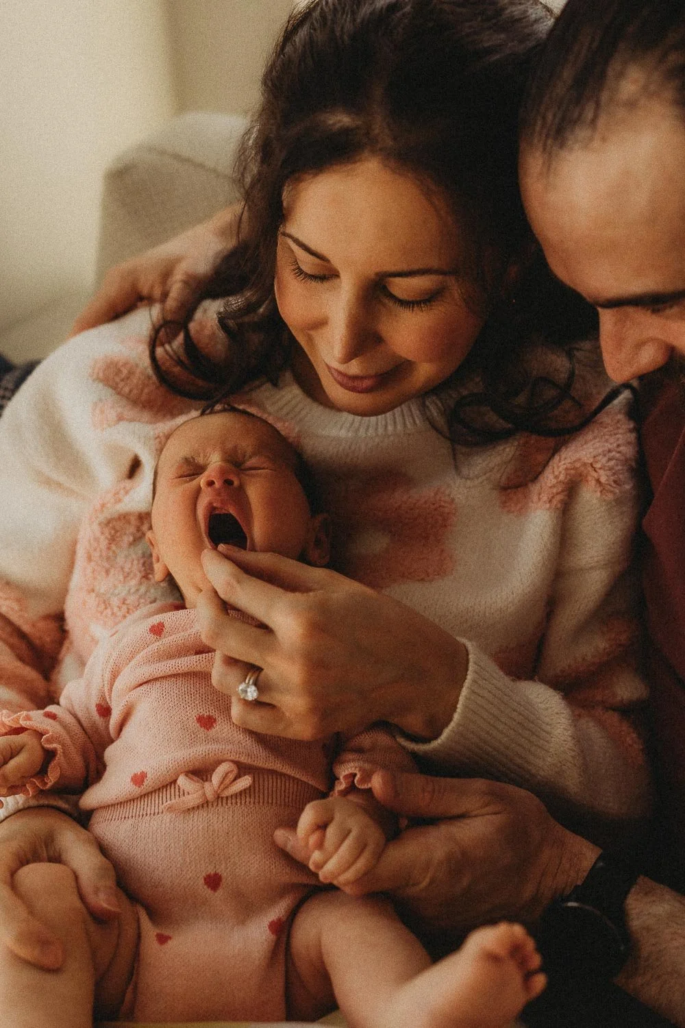 Newborn baby yawning while being held by her mom and dad, captured during an in-home newborn photo session in Dorval, Montreal