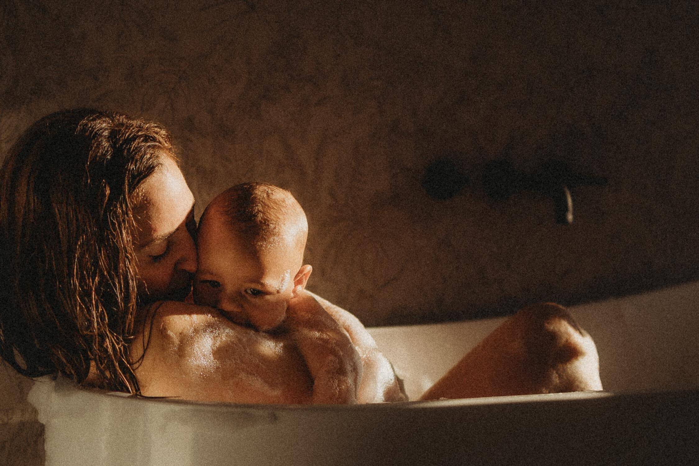 Motherhood photography session in Montreal focused on connection between mom and child while taking a bubble bath and hugging