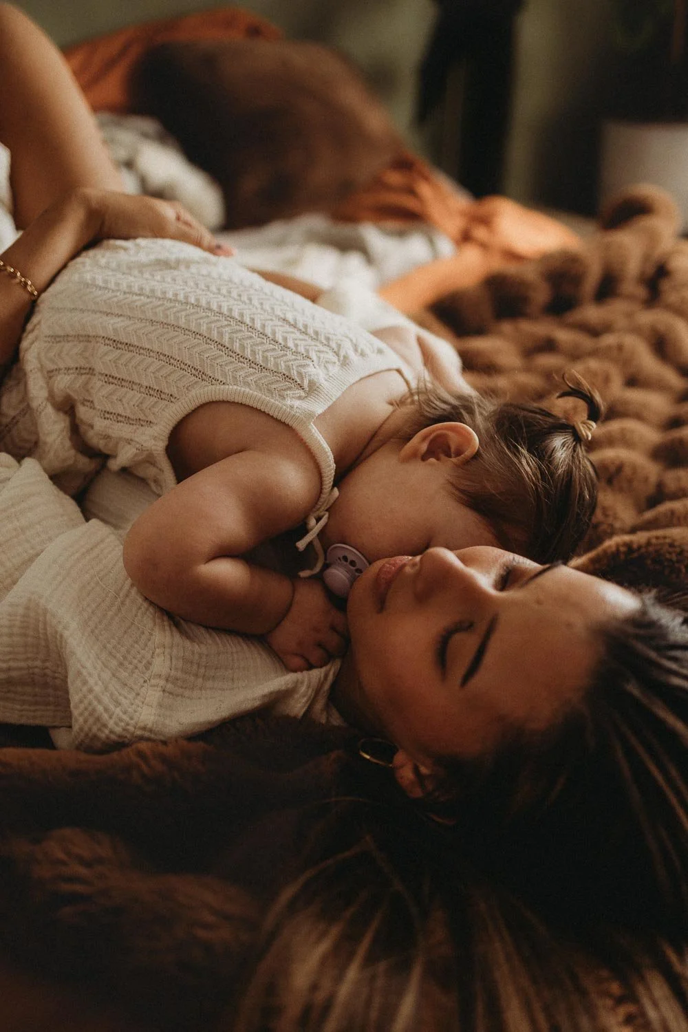 Mom and baby daughter laying down in bed while hugging, captured during a Montreal Motherhood Photo Session