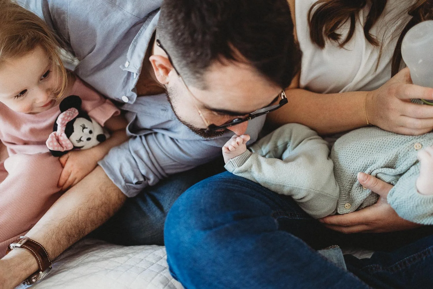 A family of four being photographed in Montreal, the dad is smelling the baby's foot while the daughter is looking with a cute smile on her face