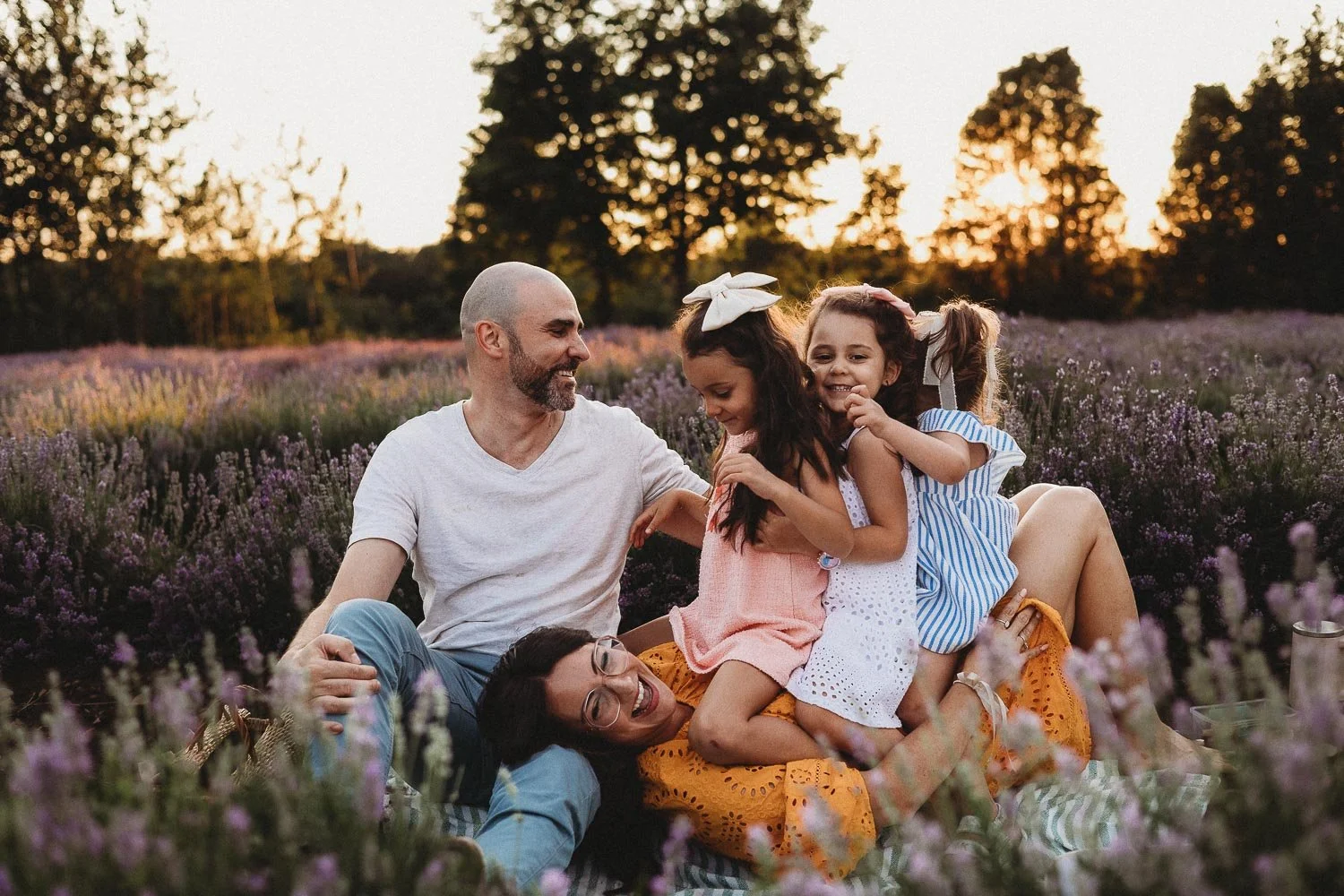 Family of five enjoying a lavender field at sunset, sitting and laughing together during an outdoor family photoshoot at La Maison Lavande, Quebec