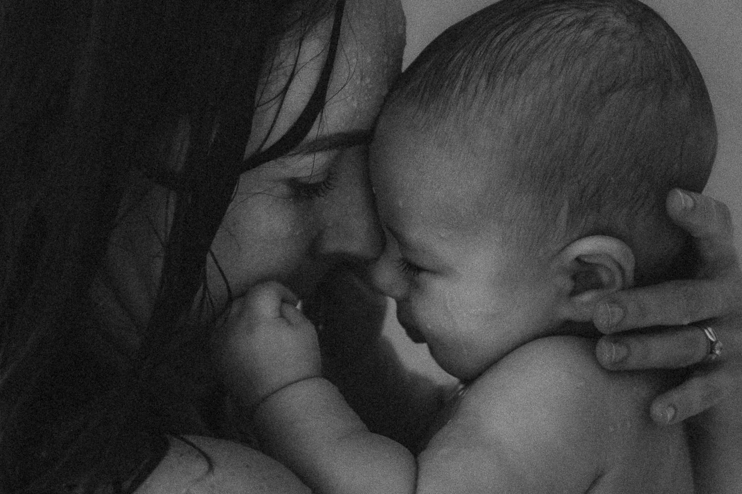 Black and white photo of a mother and her baby touching foreheads and eyes closed, displaying affection captured during an intimate shower motherhood photoshoot in Dorval, Montreal