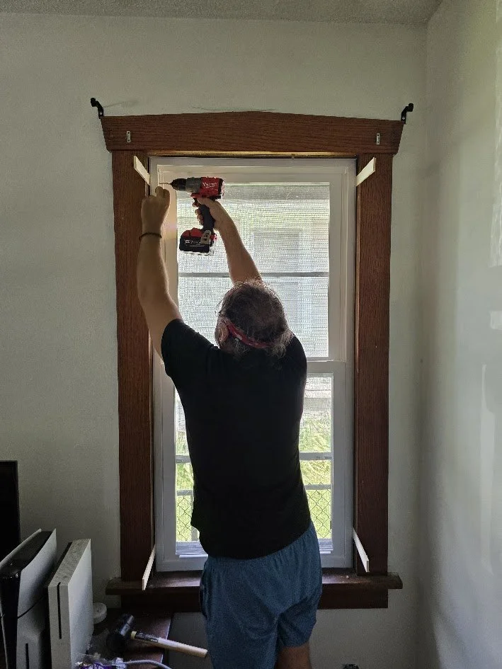 Contractor installing a new double-hung replacement window in a residential home to improve energy efficiency and insulation.