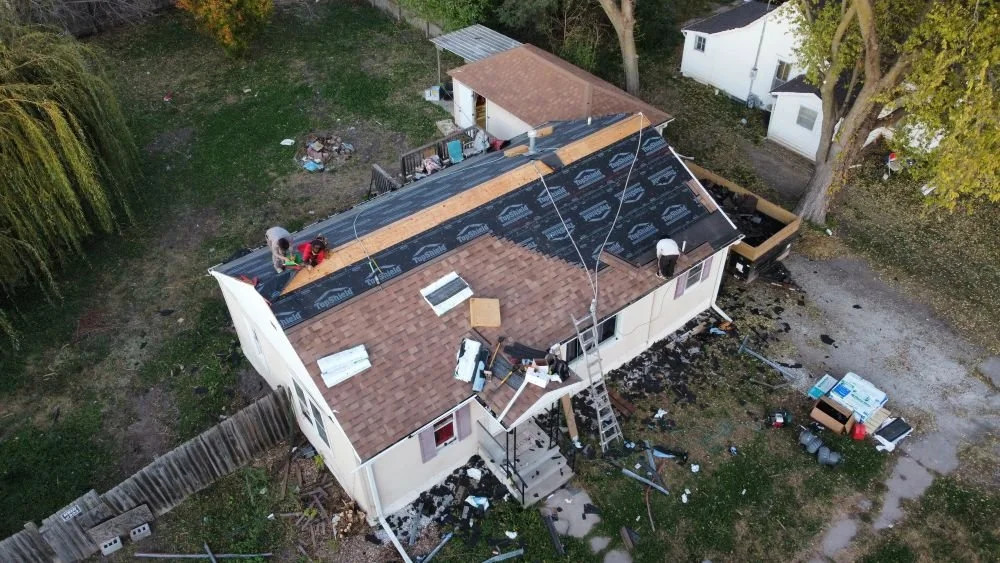 Overhead photo of Omaha roof being replaced with new shingles. Image shows exposed underlayment, exposed roof deck, and new shingles being installed