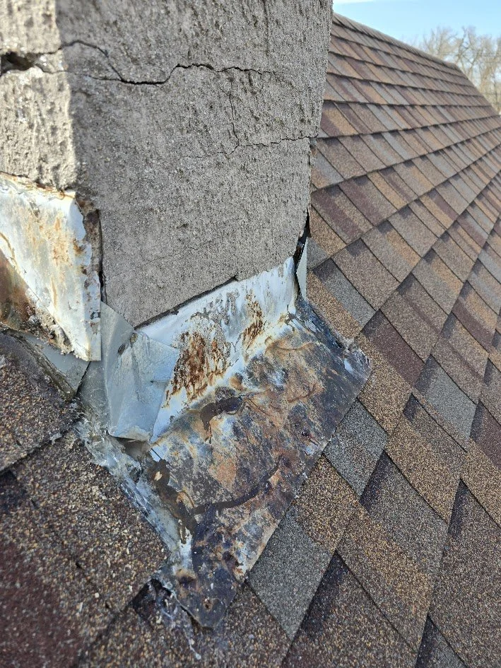 rusted chimney flashing where roof meets chimney showing common roof leak area