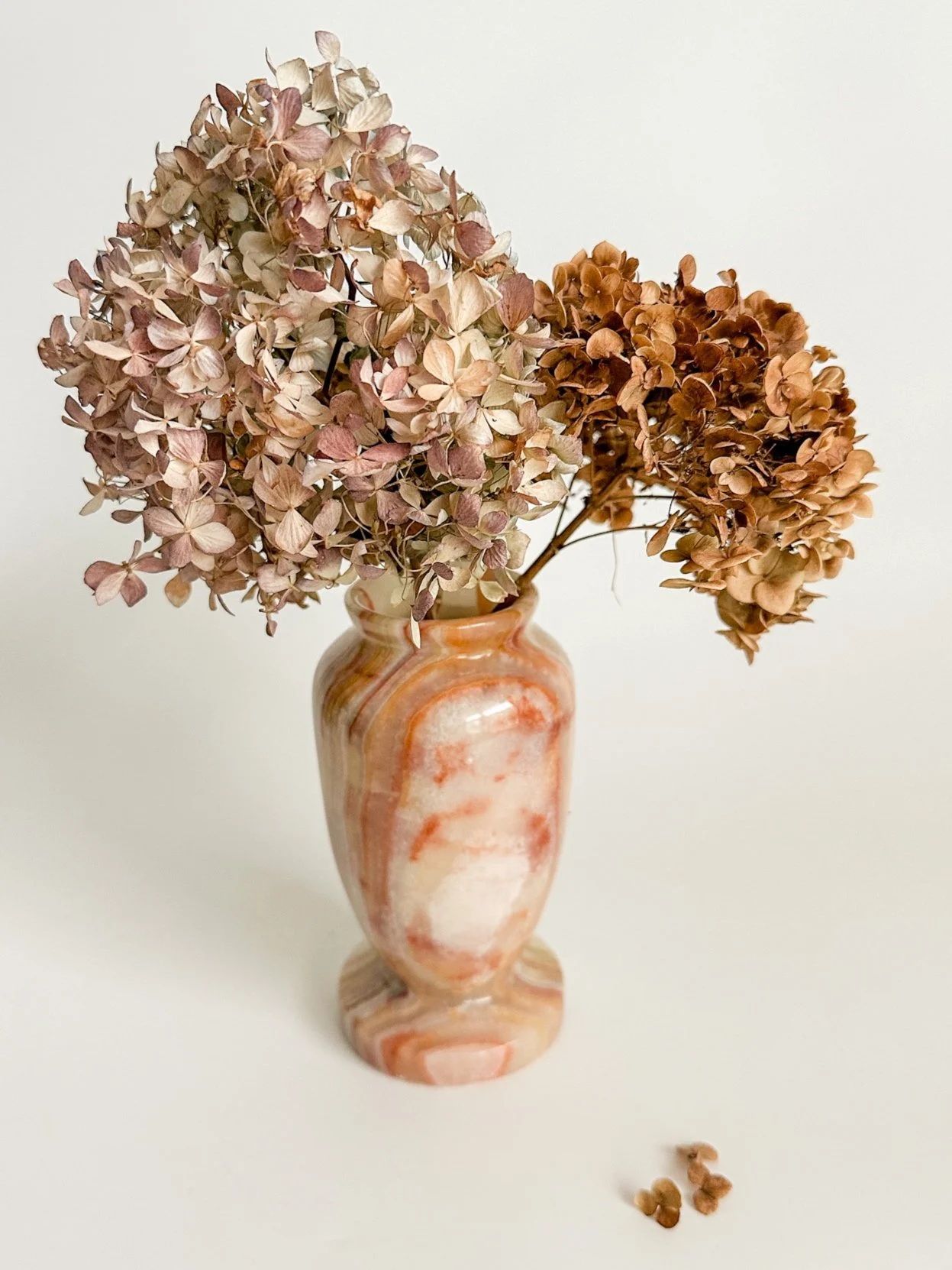 An onyx stone vase filled with a dried floral arrangement