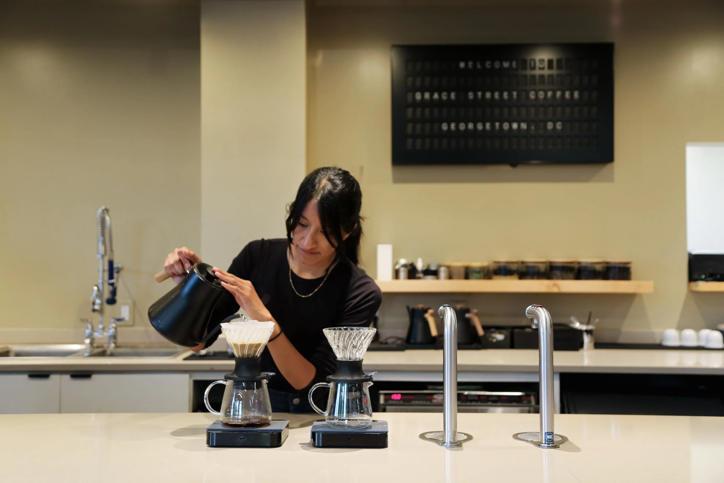 woman behind counter pours into v60 dripper. Photo by Cora Wang