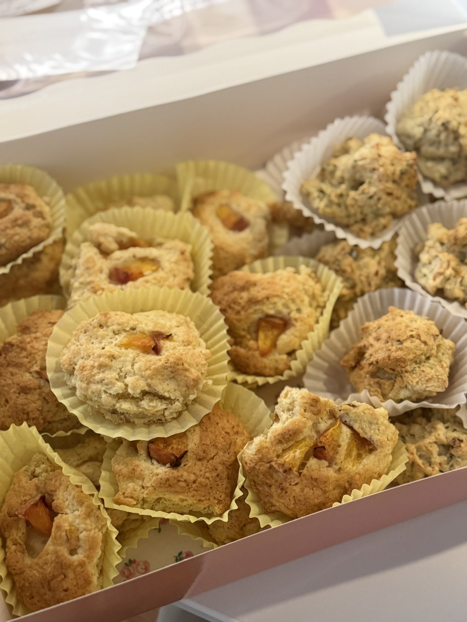 Assorted cookies in a box, some with fruit pieces, sitting in paper cups.