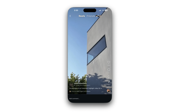 A woman standing outside in front of a house with a landscaped yard, wearing a black sleeveless top and wide-leg pants, looking at the camera.