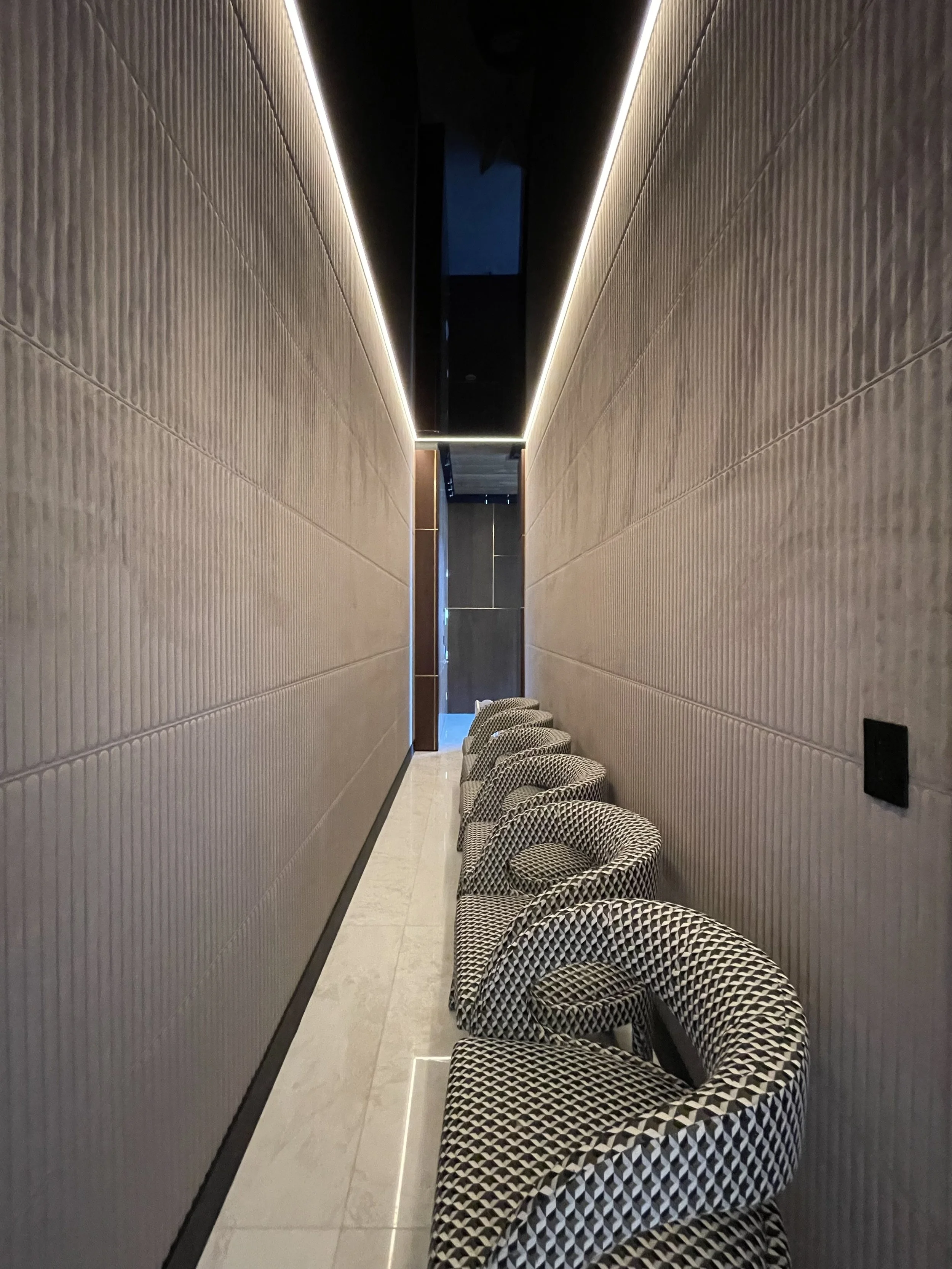 Modern hallway with geometric textured walls and black and white patterned chairs.