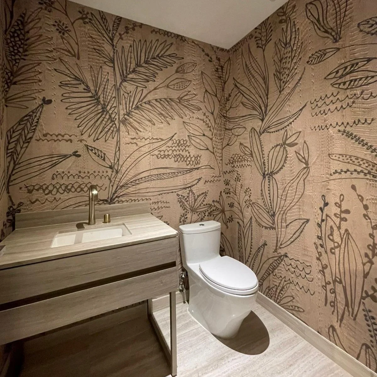 Modern bathroom with a white toilet and wooden sink, featuring botanical-themed wallpaper.