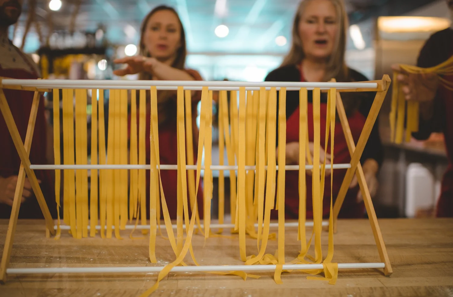 Fresh pasta drying on a rack as two guests look on