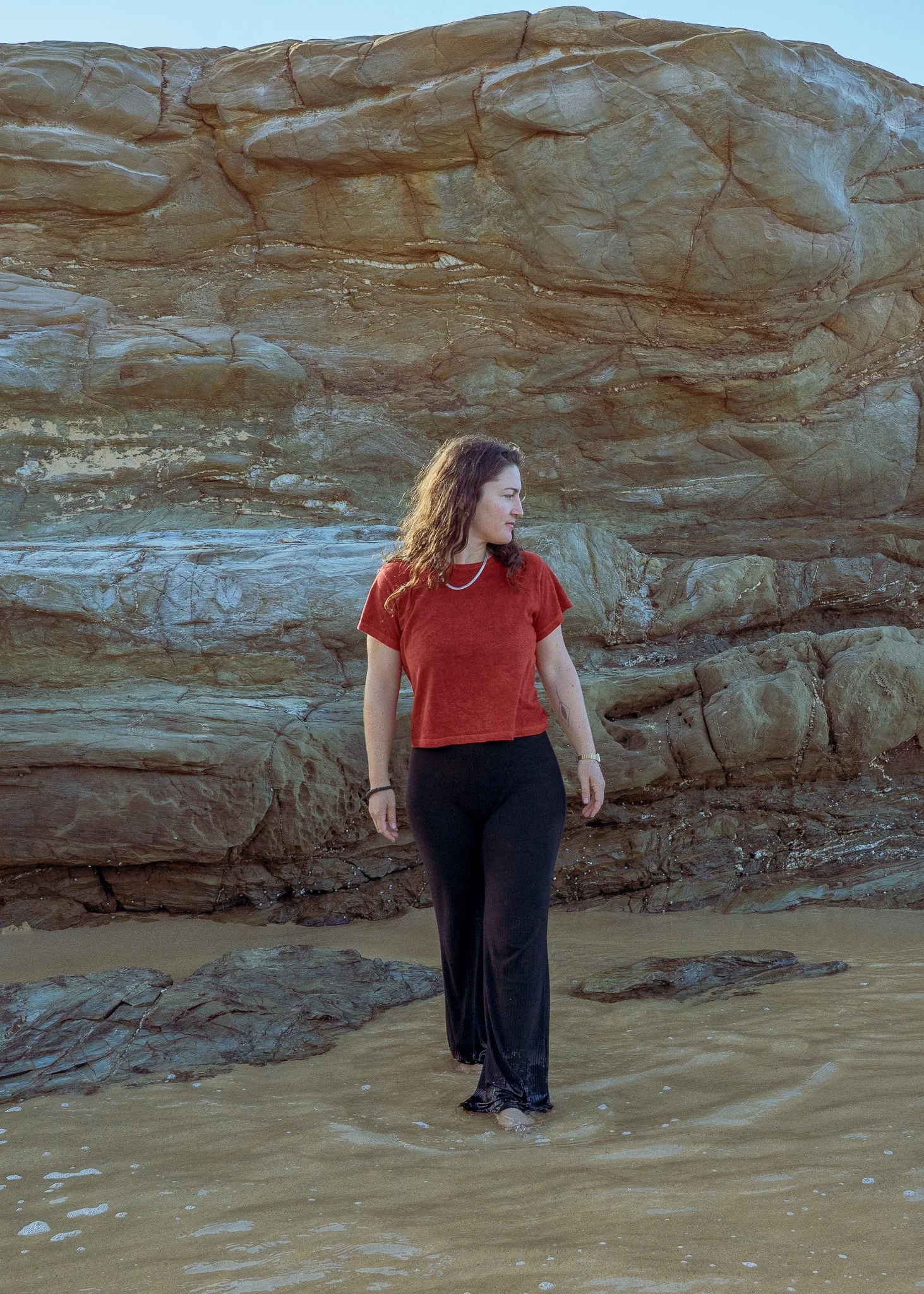 Women's cropped plant dyed hemp tee in marigold red, worn on the beach