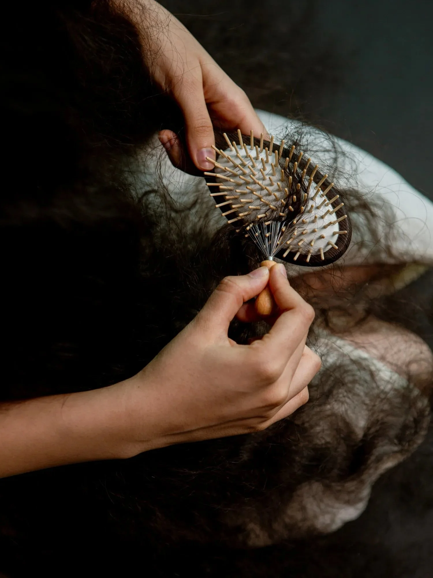 Wooden hair brush held in two hands, close-up of the bristles