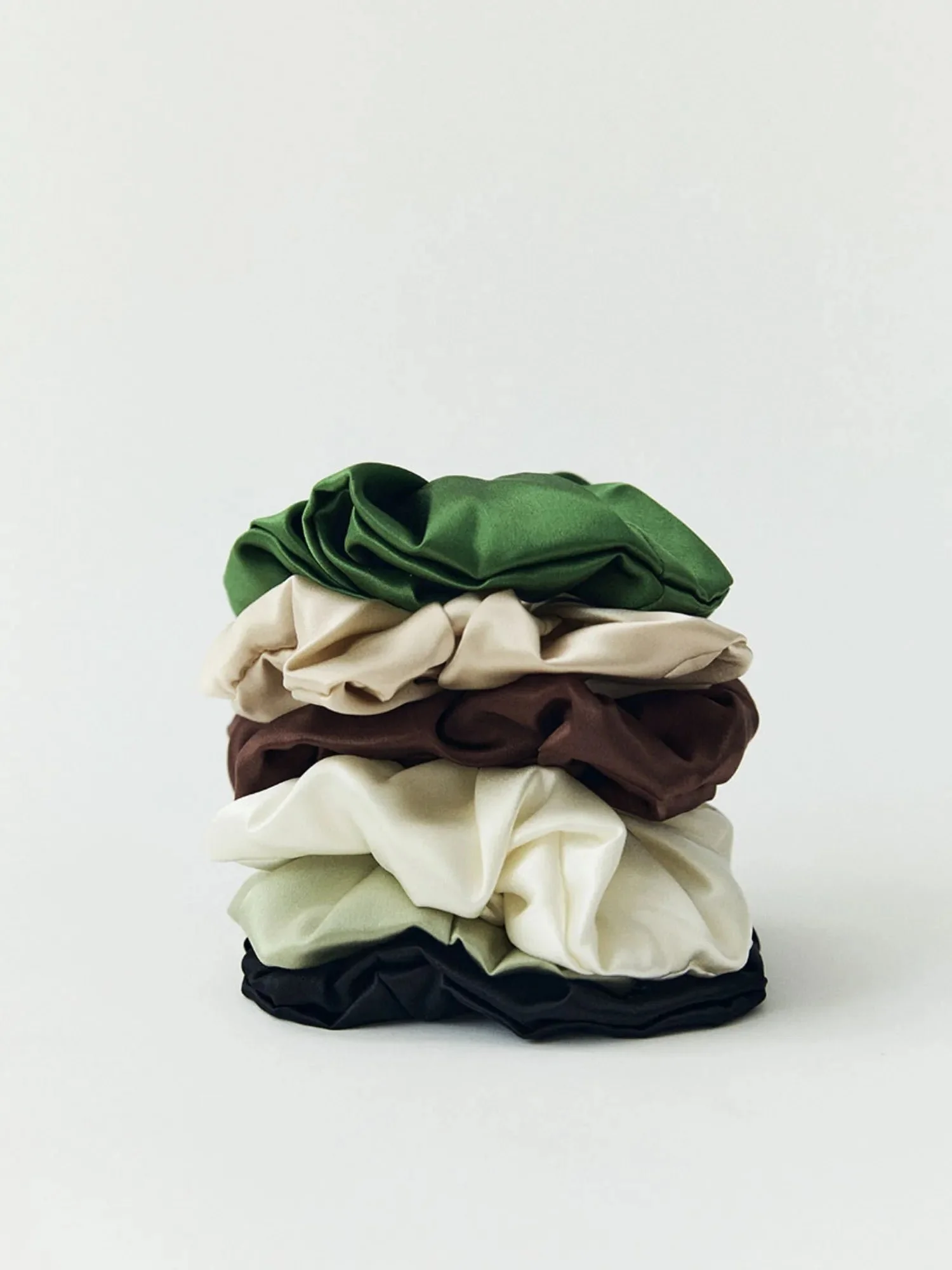 Mulberry silk scrunchies stacked in several colours, on white