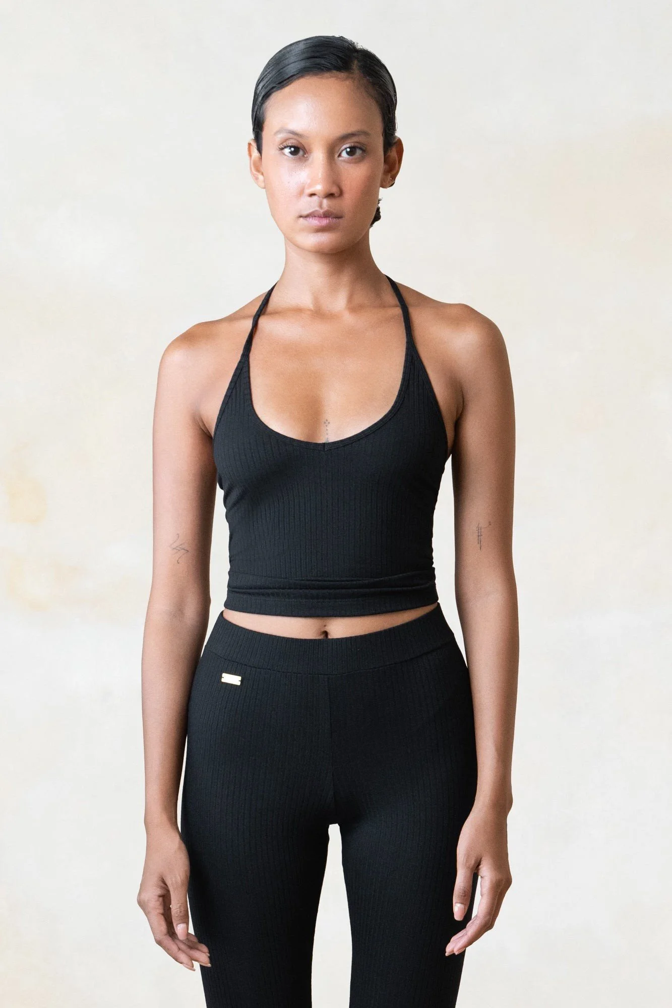 Women's ribbed ECOVERO halter top in black, worn with matching pants, front view