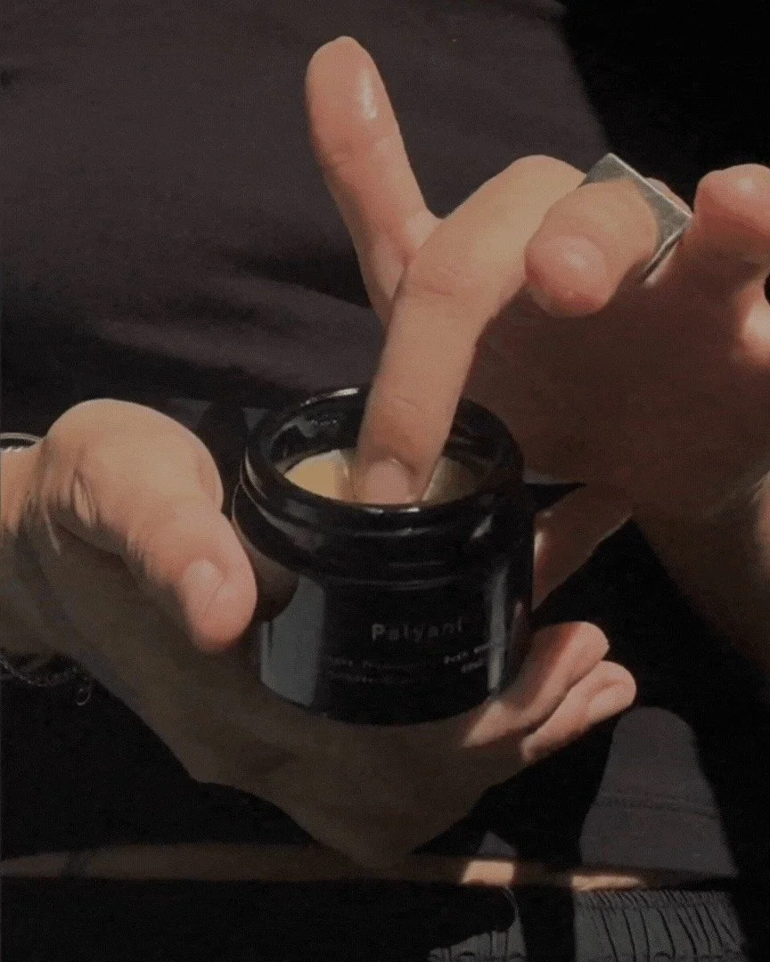 Finger dipping into an open jar of bush balm