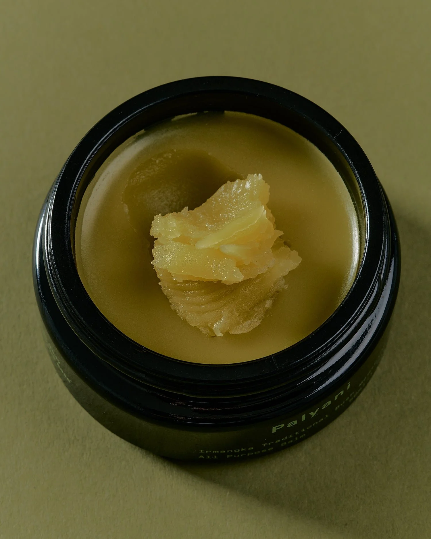 All purpose bush balm in an open black jar, close-up from above