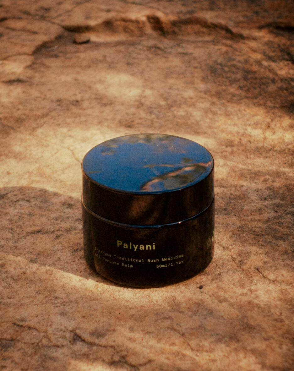 All purpose bush balm in a dark glass jar on sandstone