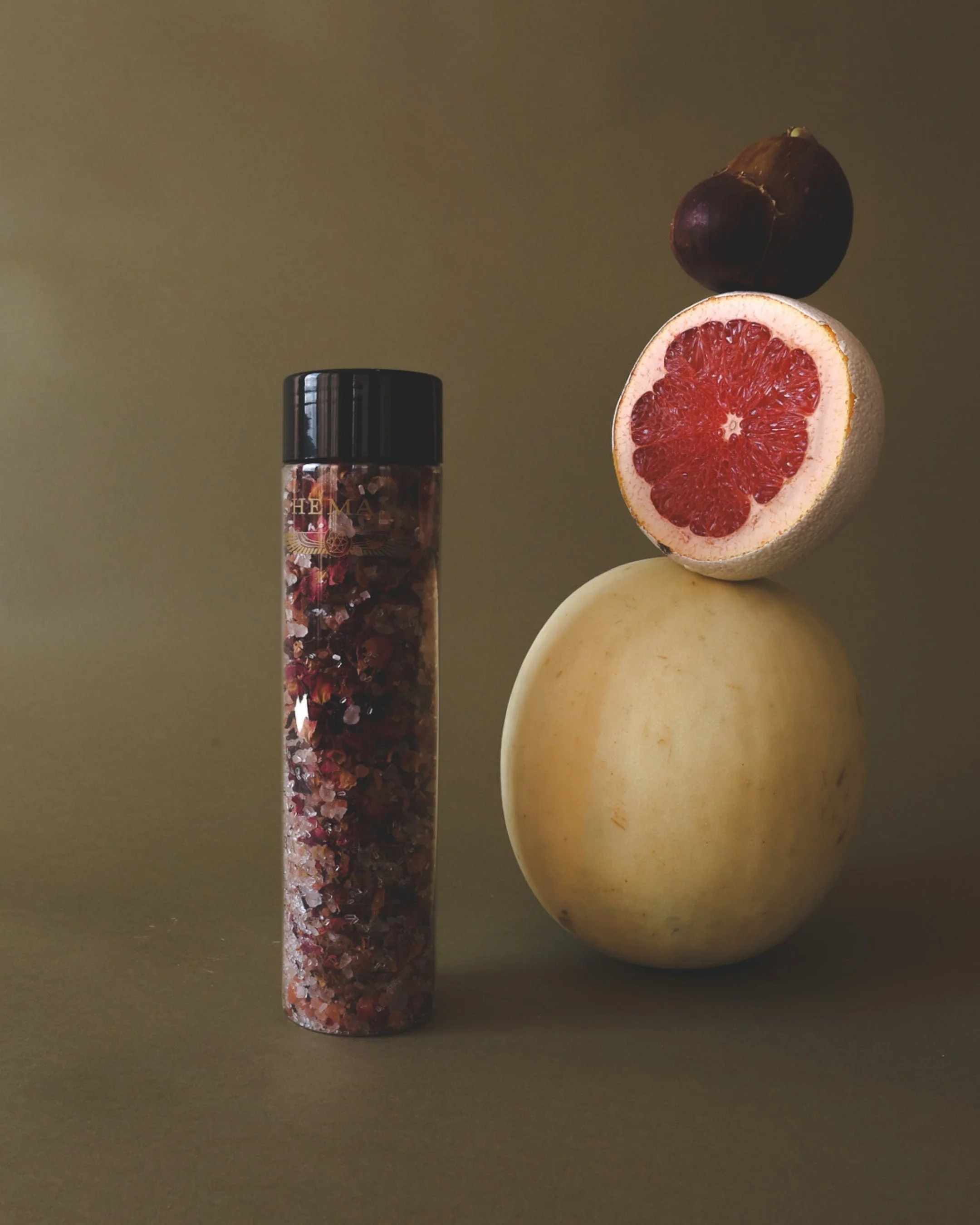 Activated mineral bath crystals in a glass tube, beside grapefruit and fruit