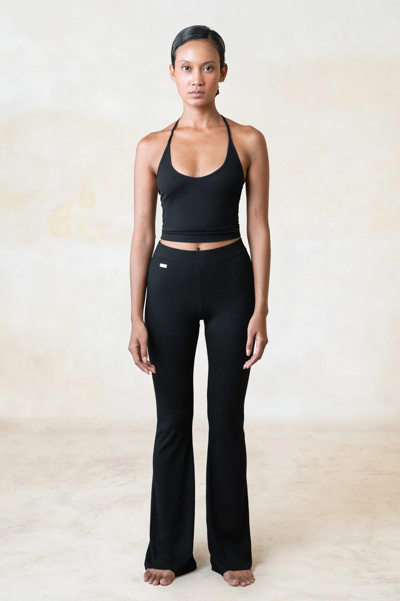 Women's ribbed ECOVERO halter top in black, worn with ribbed flares, full length