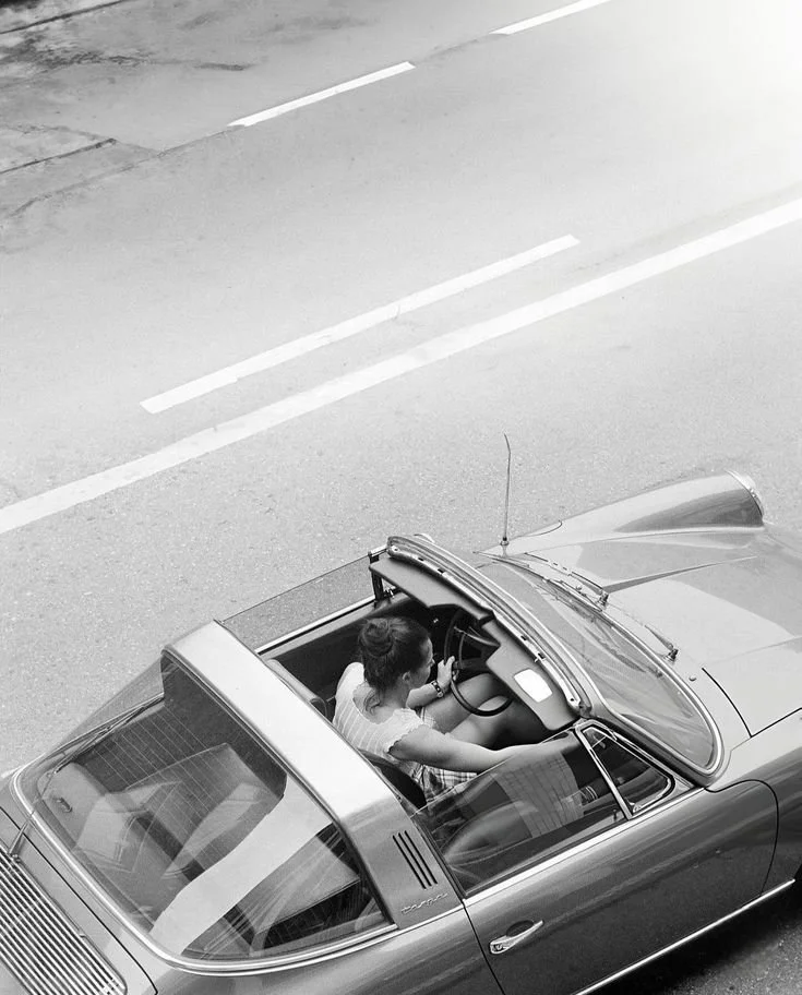 Black and white photo of a woman driving in a fancy car