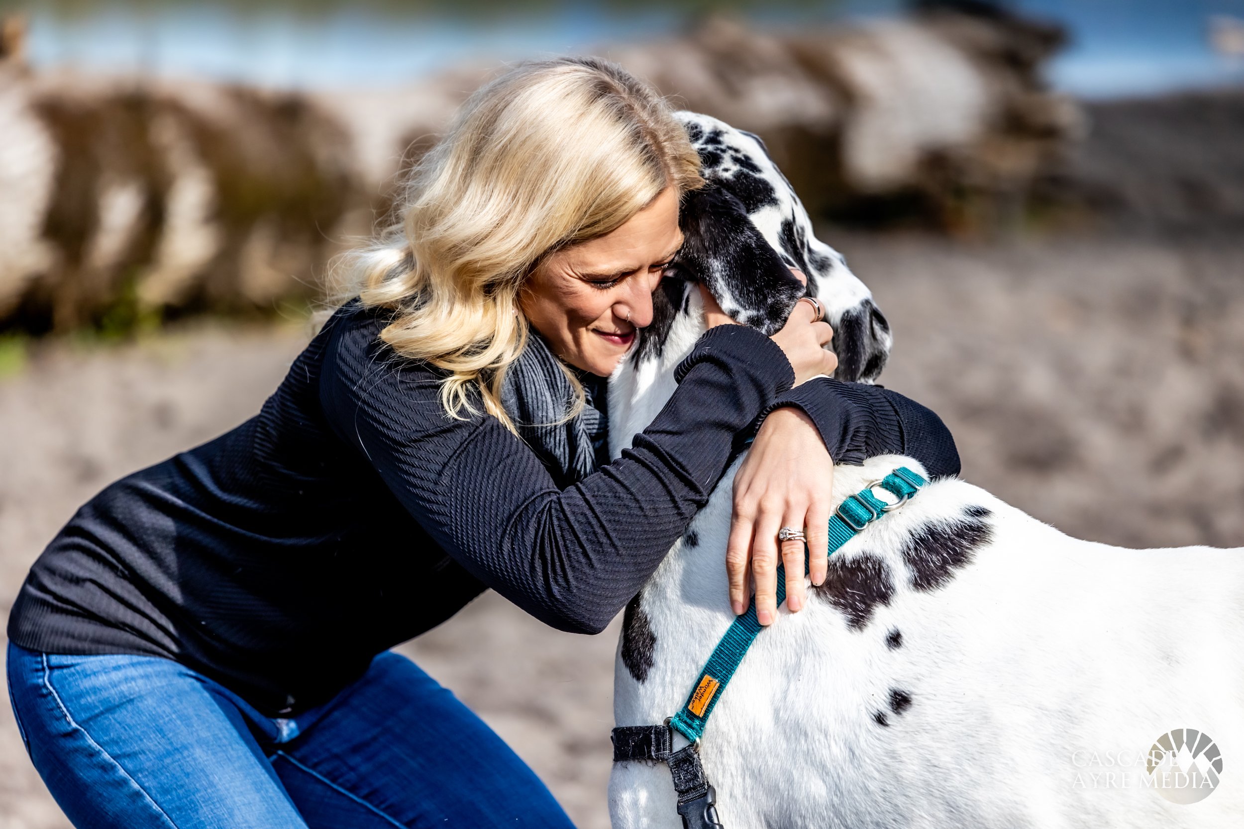 Smiling woman hugging a large black and white dog outdoors.