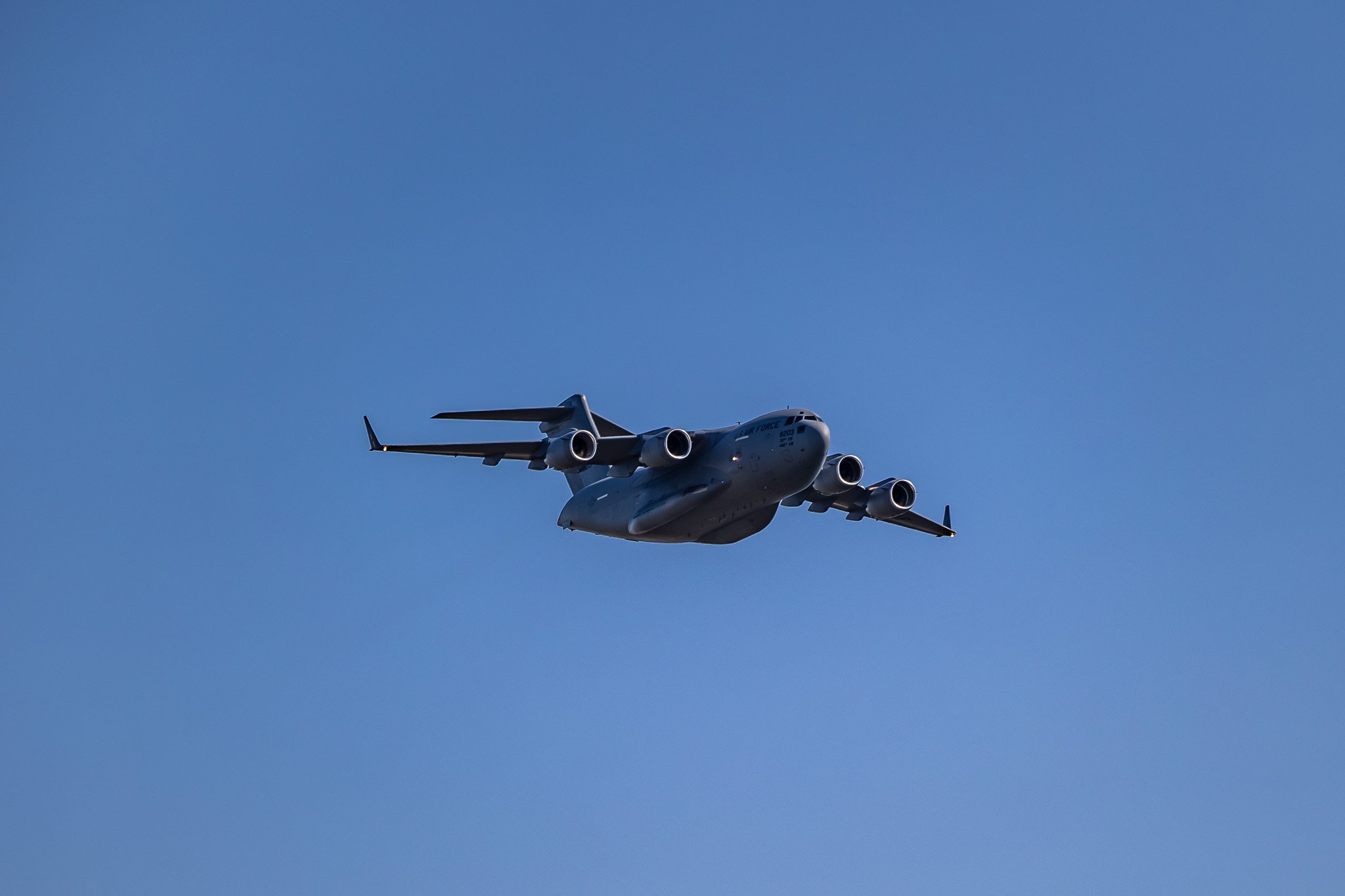 Gray military cargo plane flying in clear sky.
