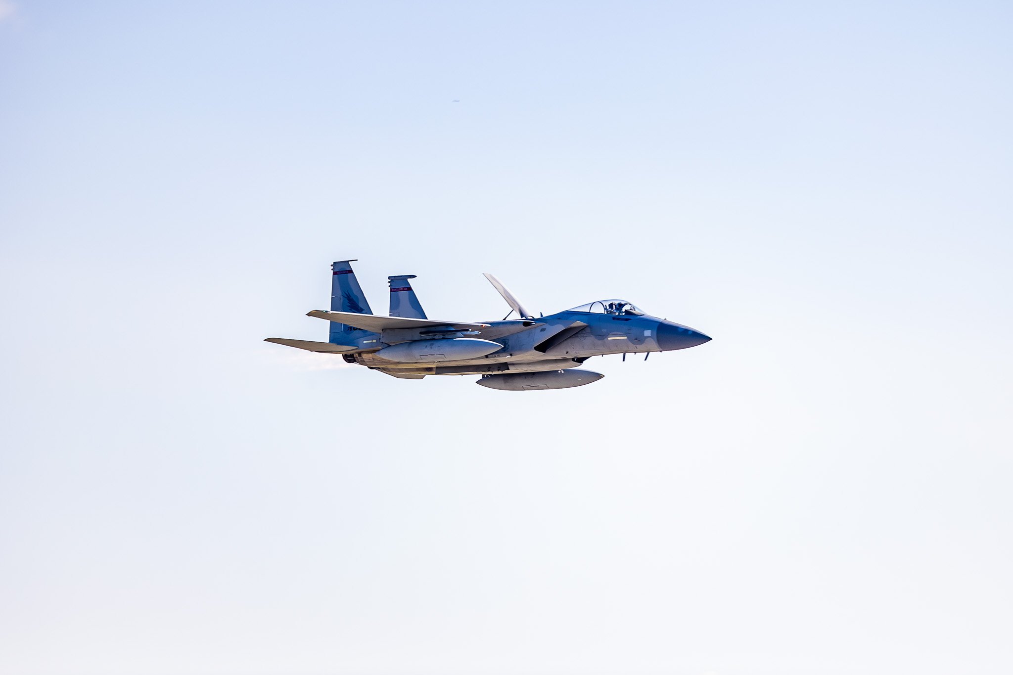 Military fighter jet in flight against clear blue sky.