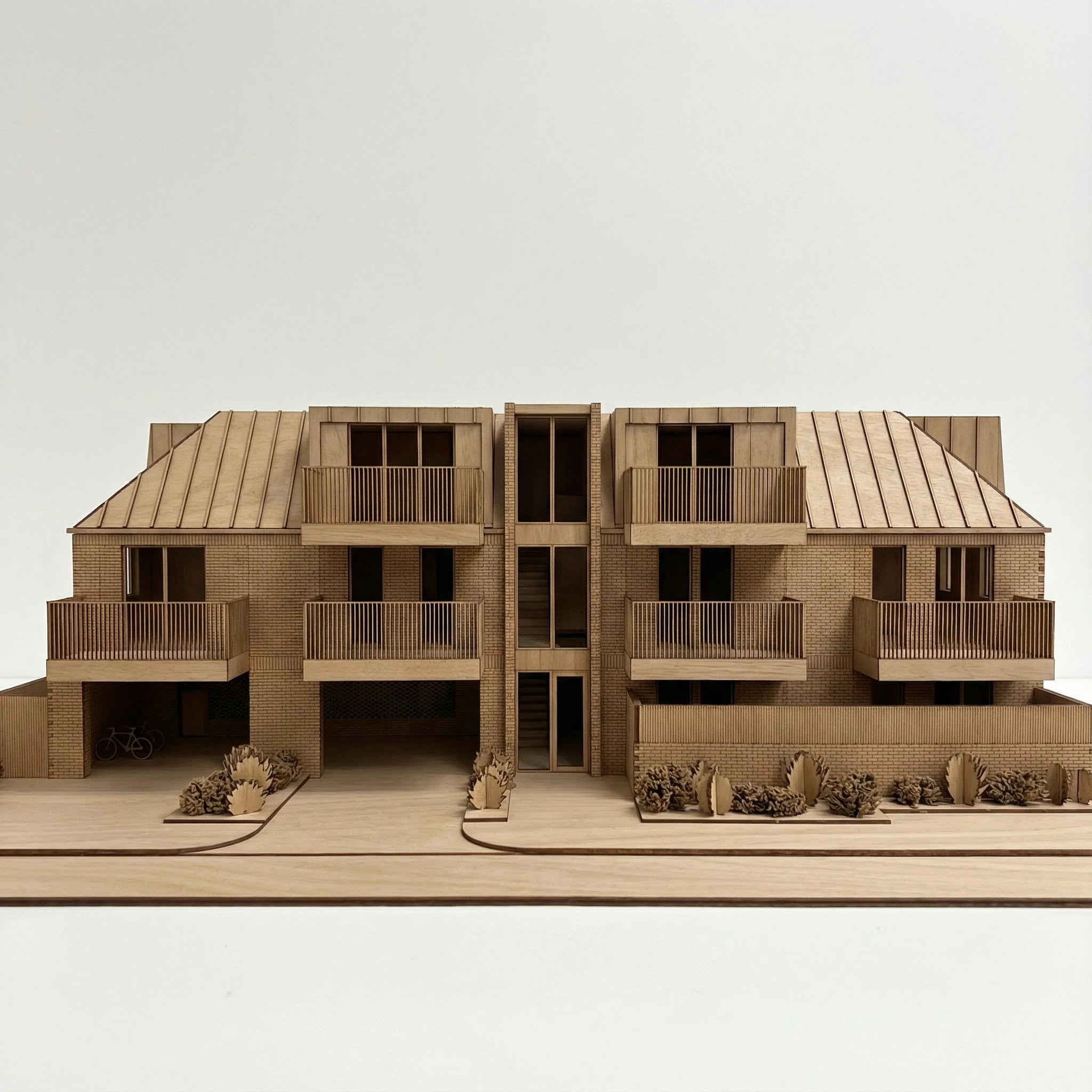 Architectural model of a modern multi-story residential building made of wood with balconies, a central staircase, landscaping, and bicycles in a parking area.