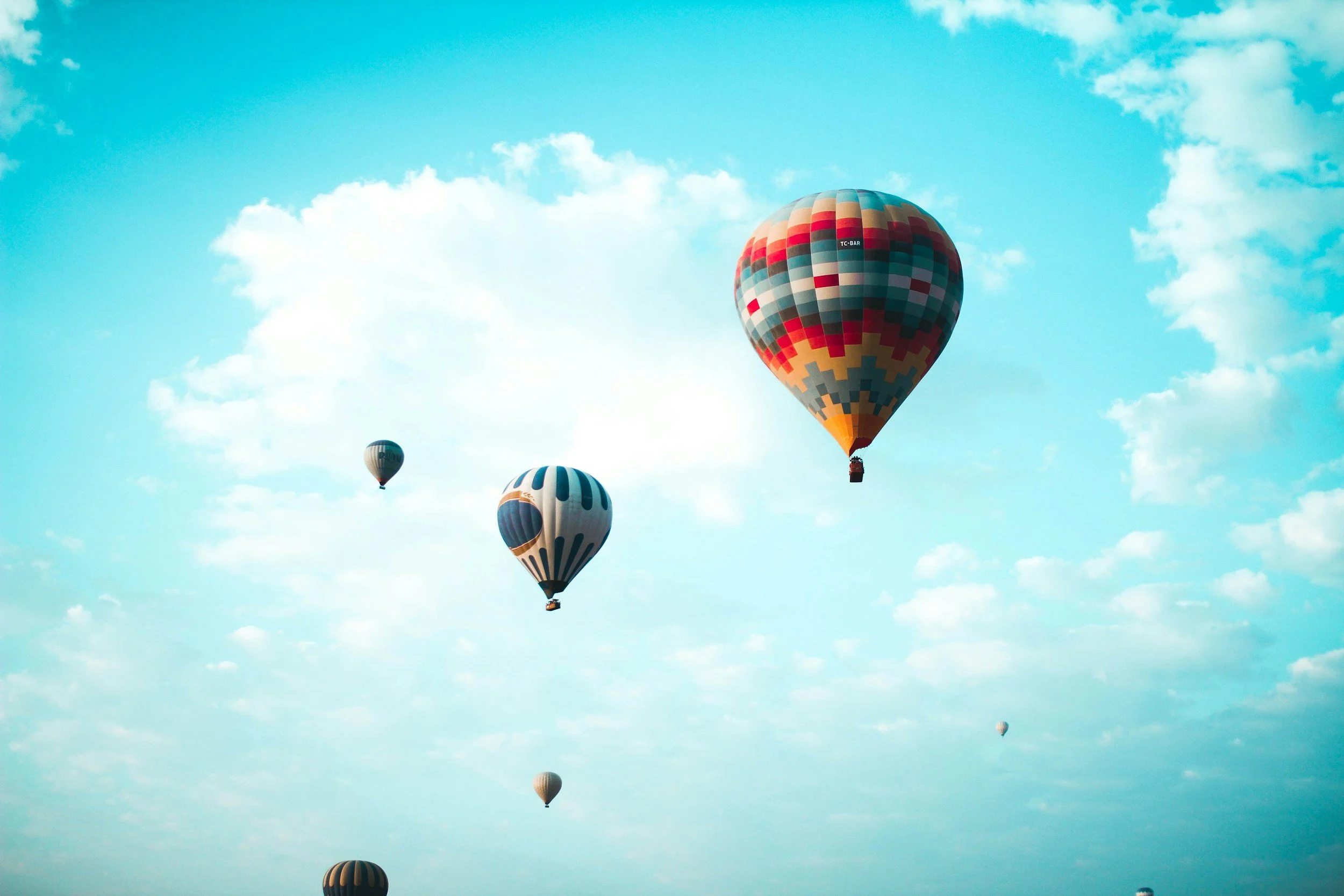 Hot air balloons in a blue sky with clouds.