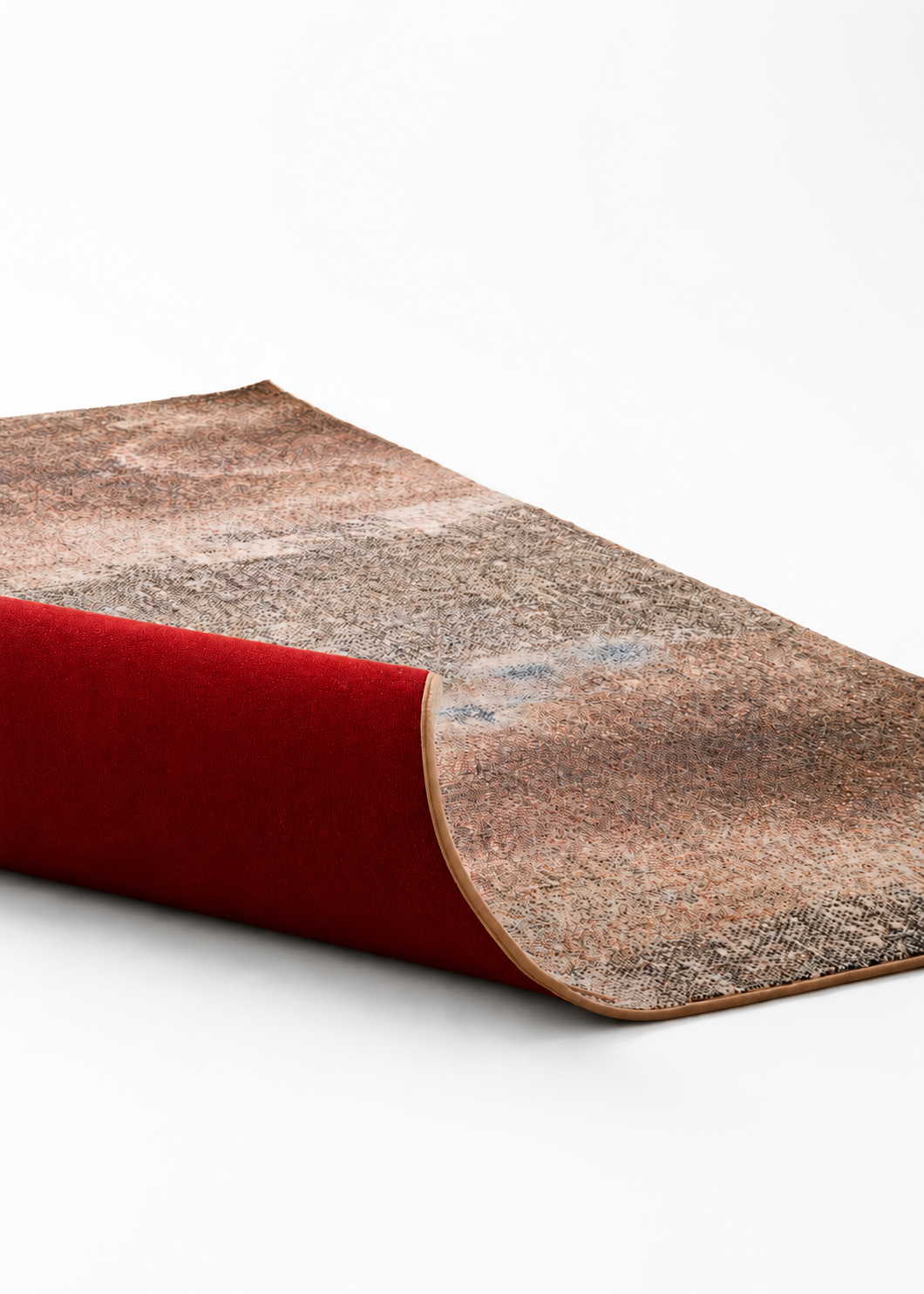 A rolled-up rug with a patterned, multicolored surface and a red backing, placed on a white background.