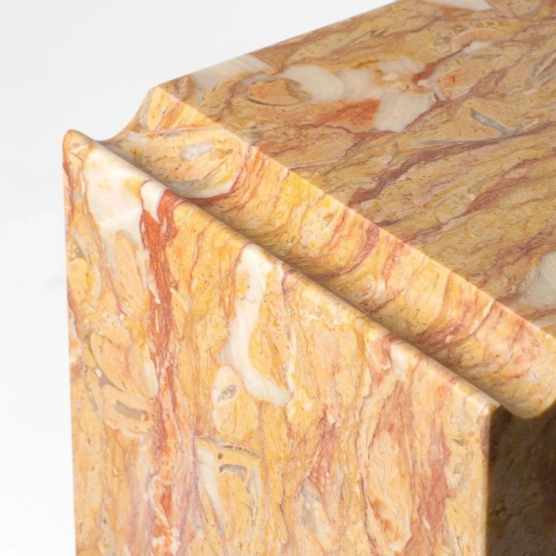 Close-up of a marble sculpture with a mix of cream, orange, and yellow veins.