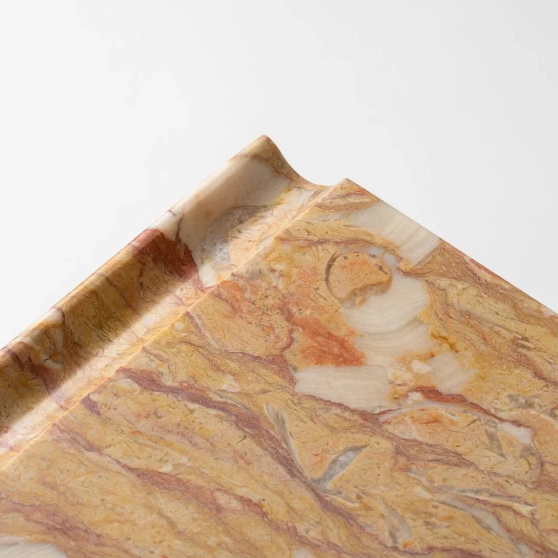 Close-up of a corner of a marble surface with beige, orange, and reddish veining.
