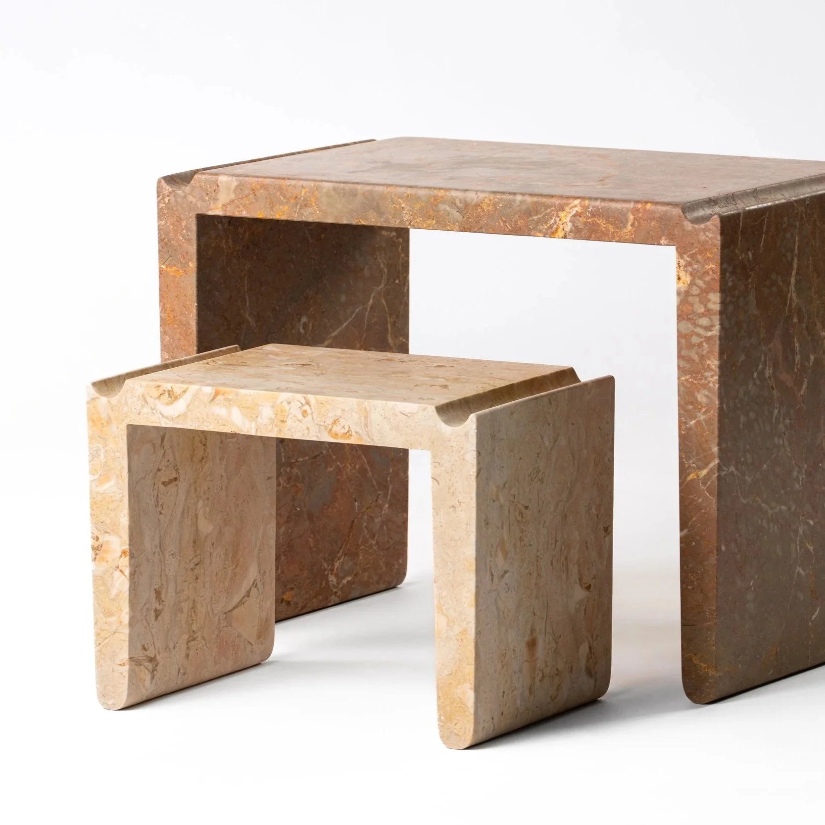 Three different marble side tables in beige, brown, and pink shades with a minimalist design.