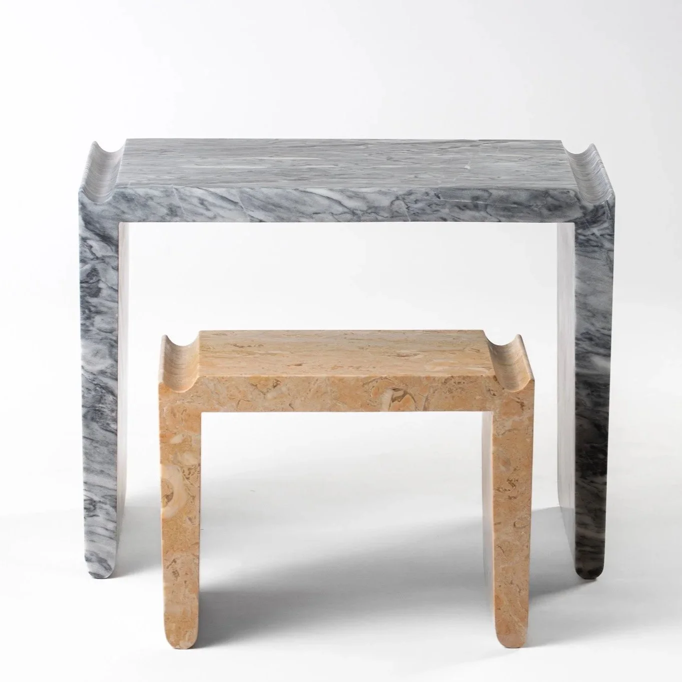 Three nested marble tables, gray, beige, and white, with curved edges, on a white background.