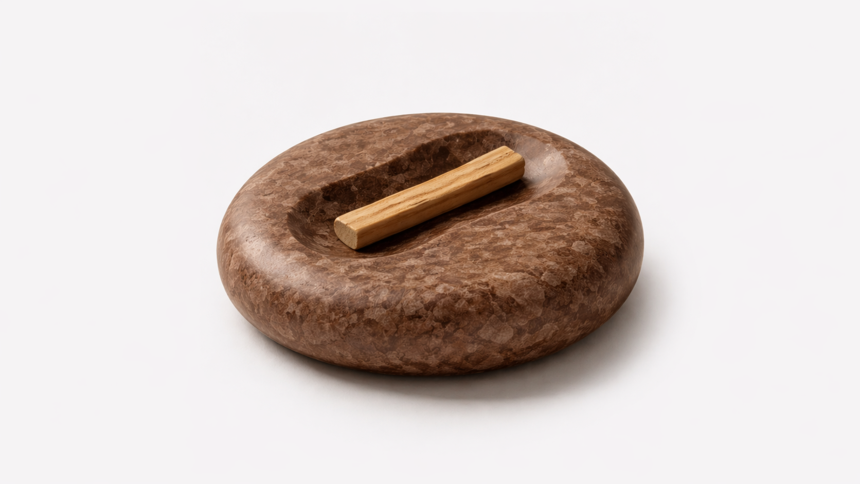 Round brown stone holder with a rectangular wooden stick placed in a carved-in circular depression.